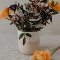 Handgemachter Steingut Becher mit Frischen bunten Blumen darin. Auf dem Becher ist eine Prägung mit "Oma" und einem Herzen. Becher von Eulenschnitt.
